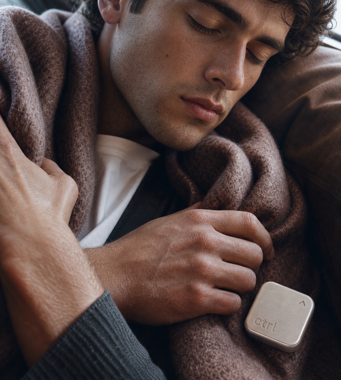 A man asleep under a wool blanket with the ctrl key resting on it