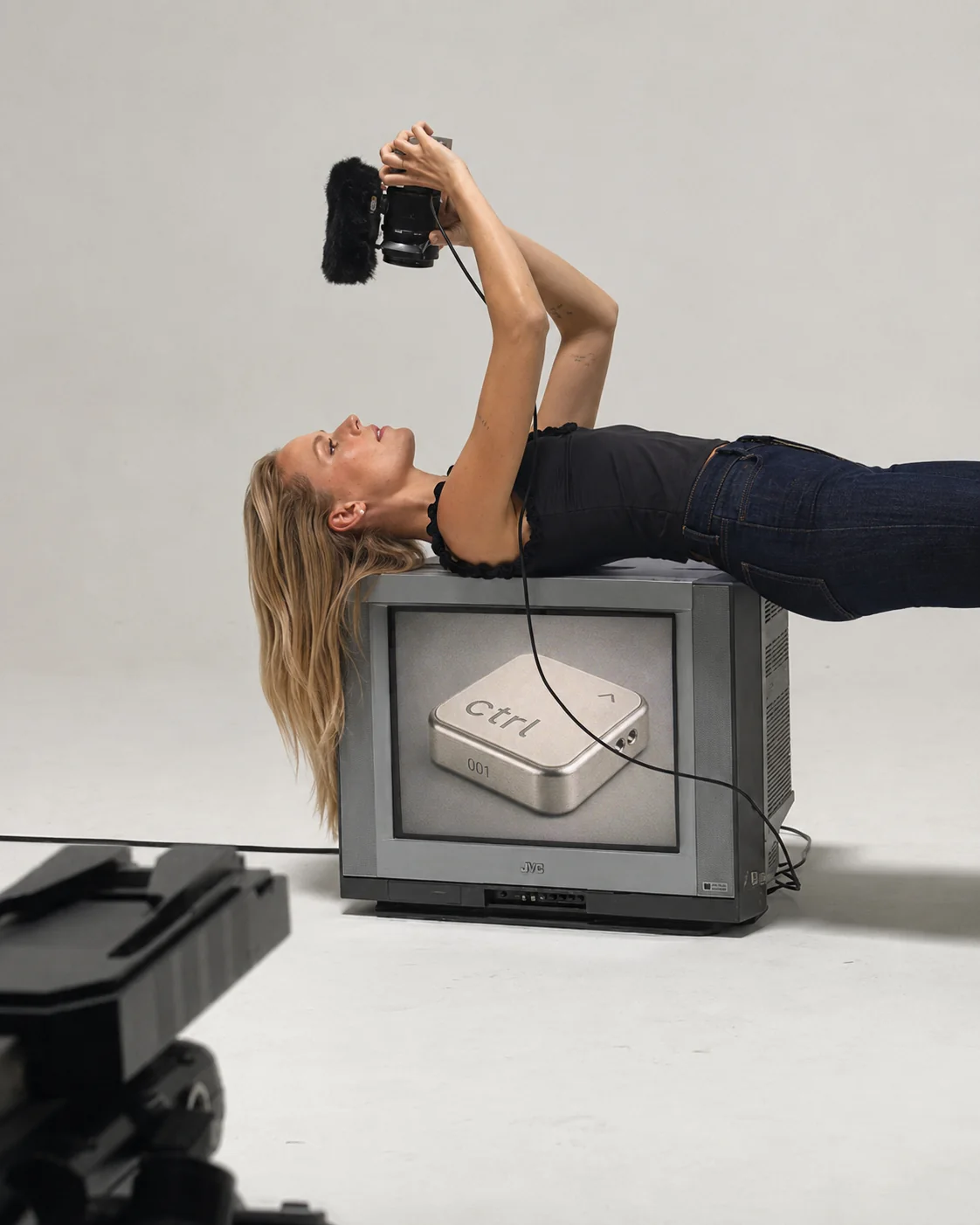 Studio shot: a woman filming herself while lying on a vintage TV that shows the ctrl key